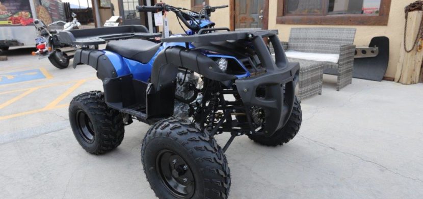 A blue and black atv parked in front of a building.