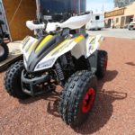 A white and yellow atv parked on the side of road.