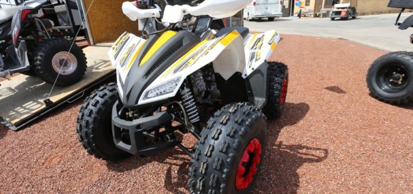 A white and yellow atv parked on the side of road.