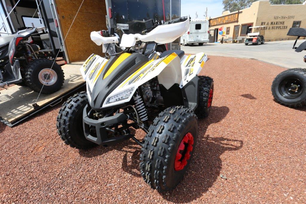 A white and yellow atv parked on the side of road.