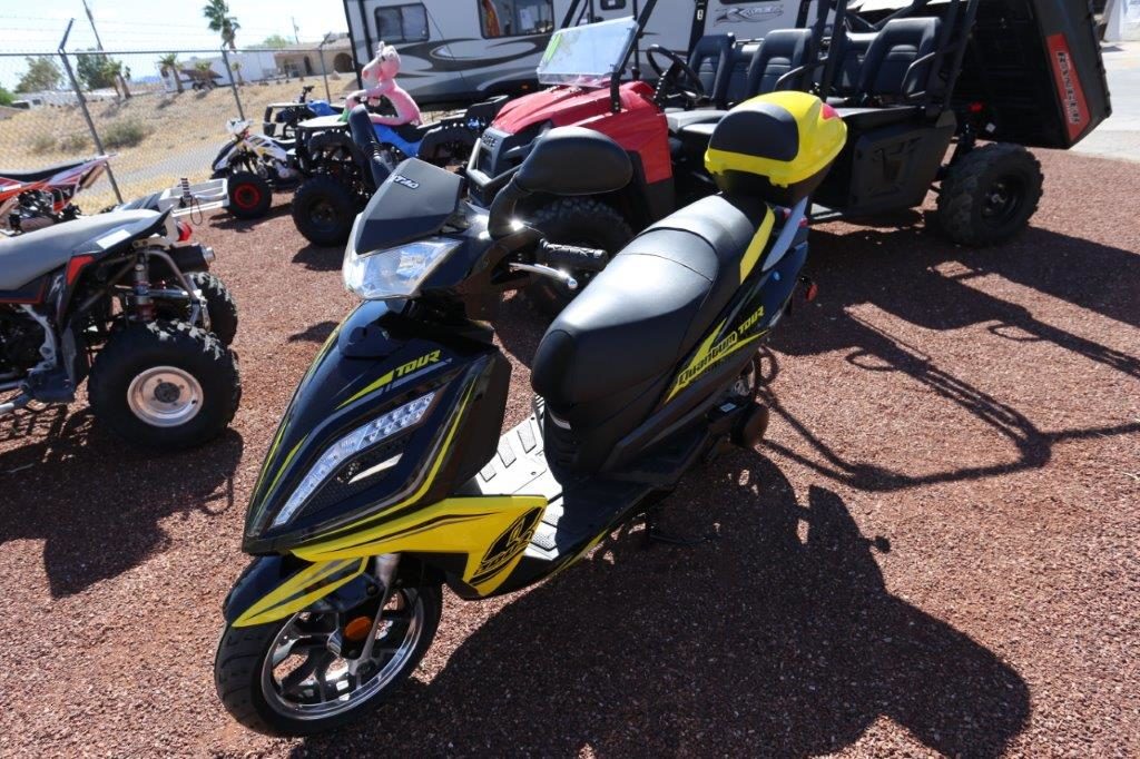 A yellow and black scooter parked on top of a dirt field.