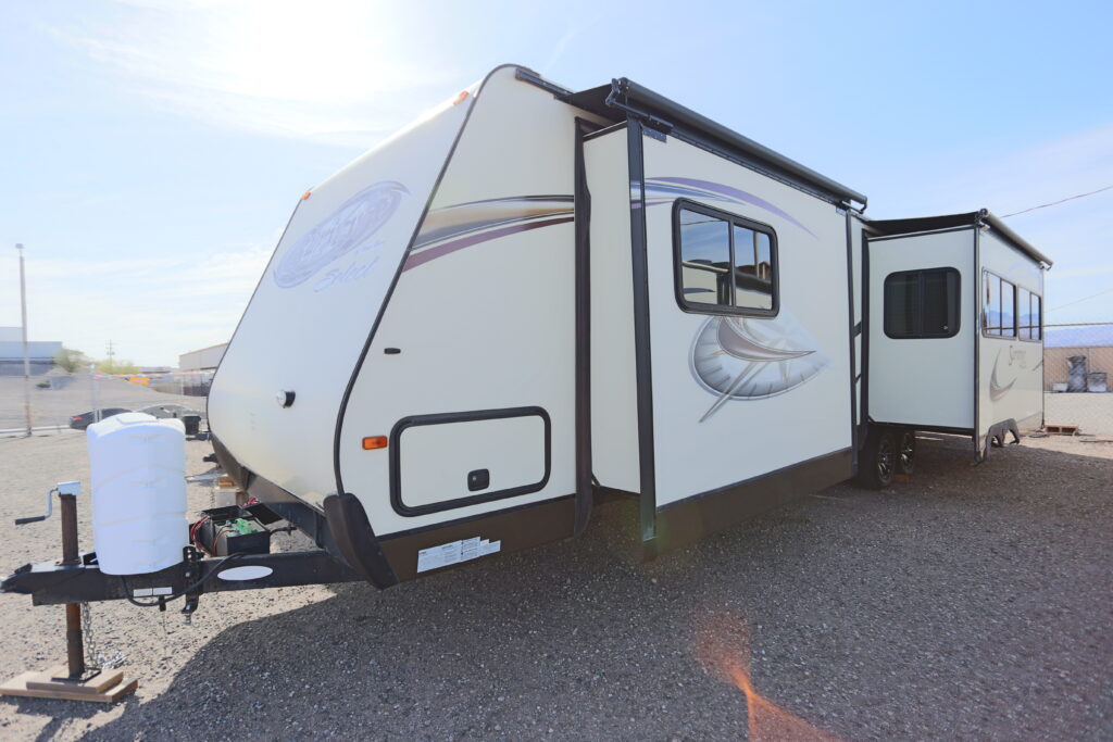 A white travel trailer parked on top of a road.