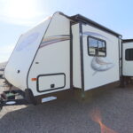 A white travel trailer parked on top of a road.