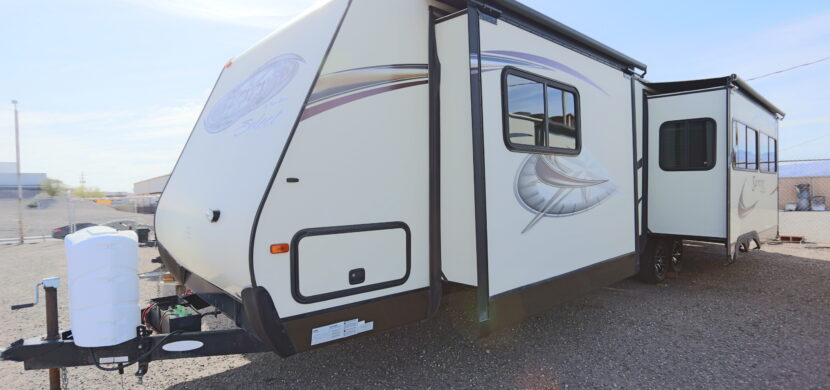 A white travel trailer parked on top of a road.