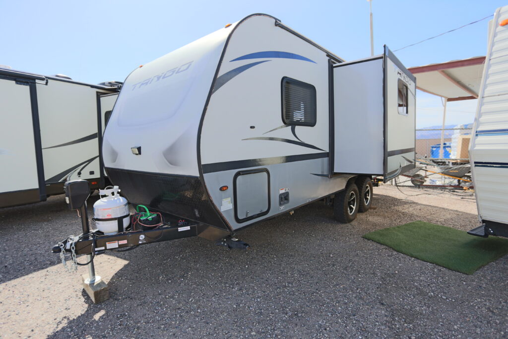 A white and blue trailer parked on top of gravel.