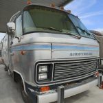 A silver rv parked in front of a building.