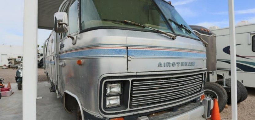 A silver rv parked in front of a building.