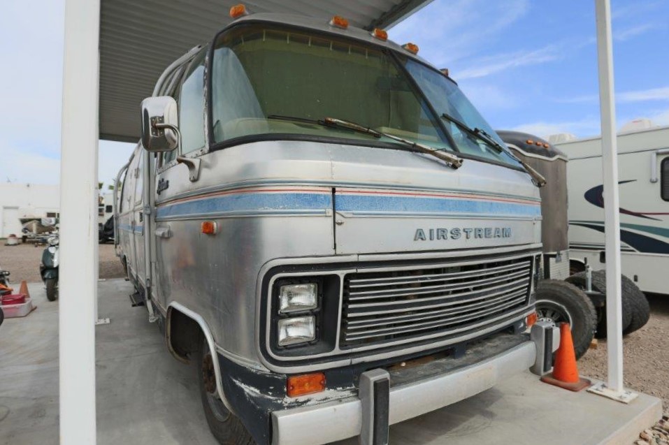 A silver rv parked in front of a building.