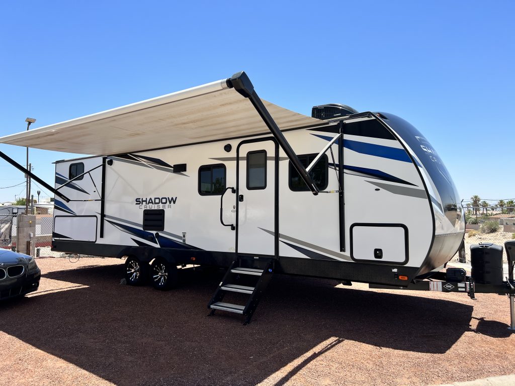 A white and black trailer with an awning on the side.