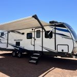 A white and black trailer with an awning on the side.