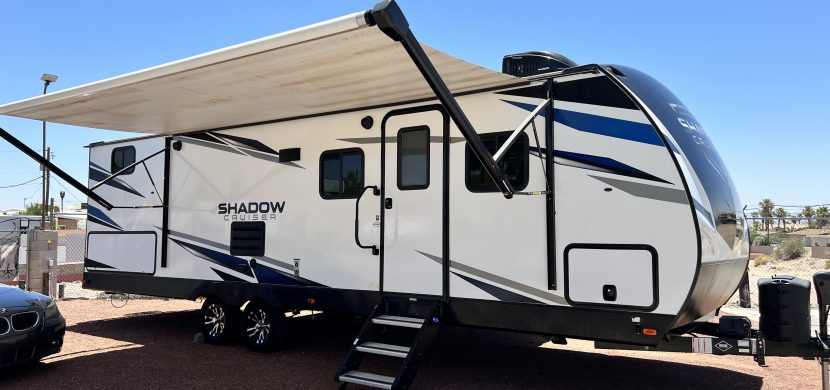 A white and black trailer with an awning on the side.