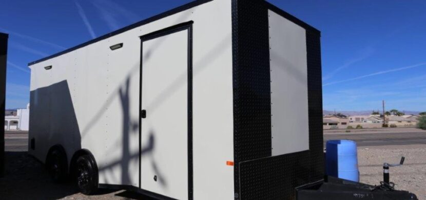 A white trailer with black trim parked on the side of road.