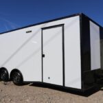 A white trailer with black trim parked on the side of road.