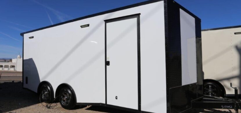 A white trailer with black trim parked on the side of road.