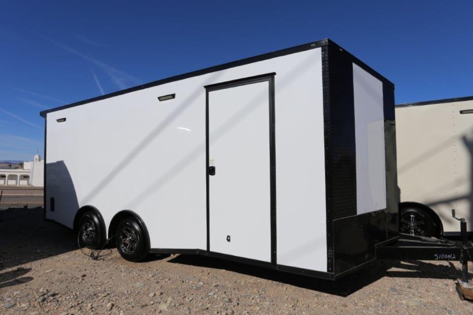 A white trailer with black trim parked on the side of road.