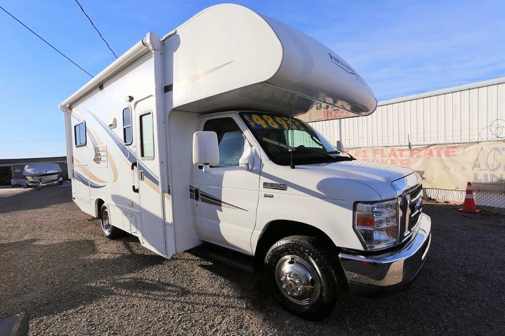 A white rv parked in the street with no one around.