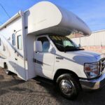 A white rv parked in the street with no one around.