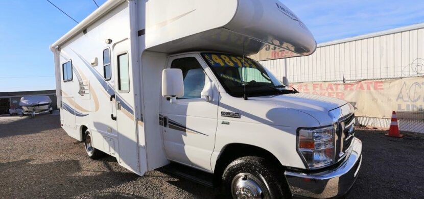 A white rv parked in the street with no one around.