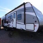 A trailer parked in the dirt with a sky background