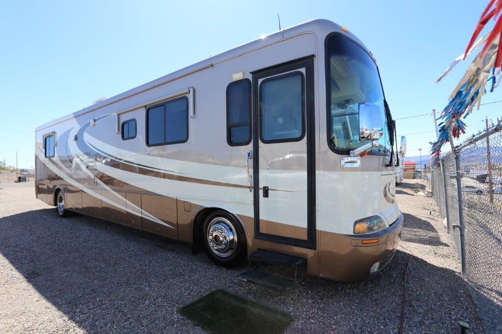 A white and brown rv parked on the side of road.