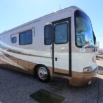 A white and brown rv parked on the side of road.