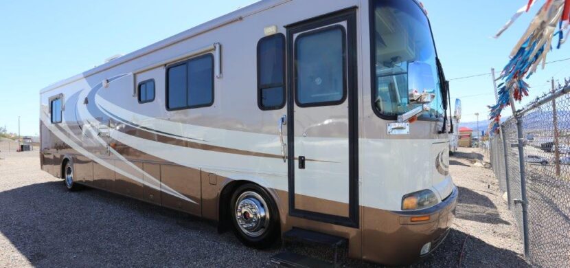 A white and brown rv parked on the side of road.