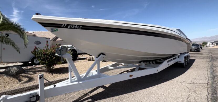 A boat is parked on the ground with its trailer.