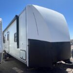 A white and black trailer parked in the sun.