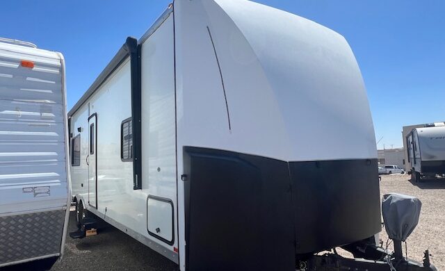 A white and black trailer parked in the sun.